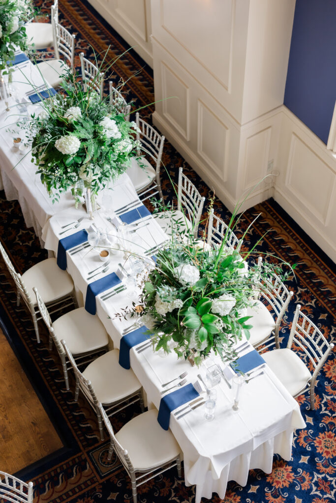 Elegant Grand Ballroom wedding reception with navy table runners, silver chairs, and candlelit centerpieces in Covington KY.