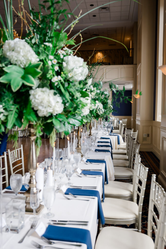 Elegant Grand Ballroom wedding reception with navy table runners, silver chairs, and candlelit centerpieces in Covington KY.