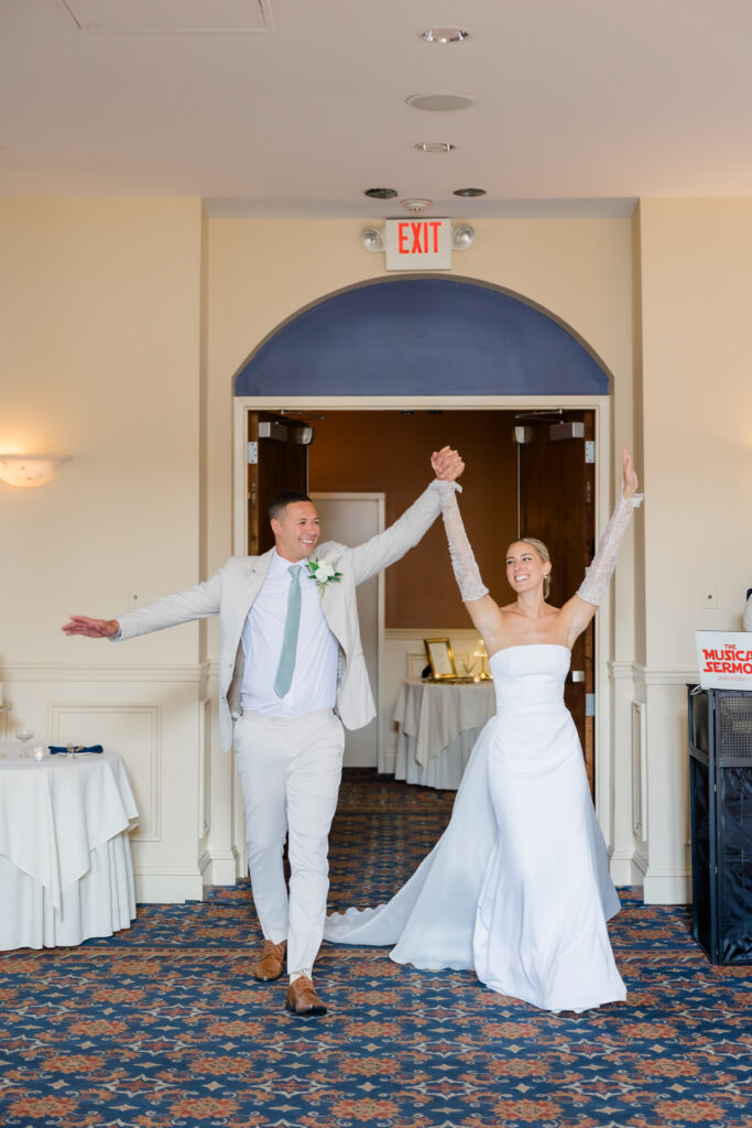 Bride and groom entering wedding reception hand-in-hand with big smiles at The Grand Ballroom in Covington KY.