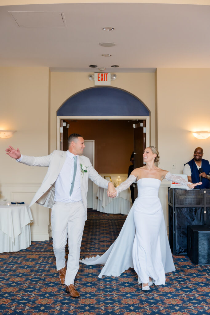 Bride and groom entering wedding reception hand-in-hand with big smiles at The Grand Ballroom in Covington KY.