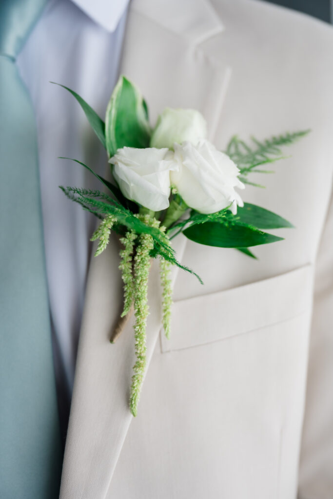 Groom in light beige suit and blue tie sitting in a modern chair, smiling before wedding ceremony at The Cathedral Basilica in Covington KY.
