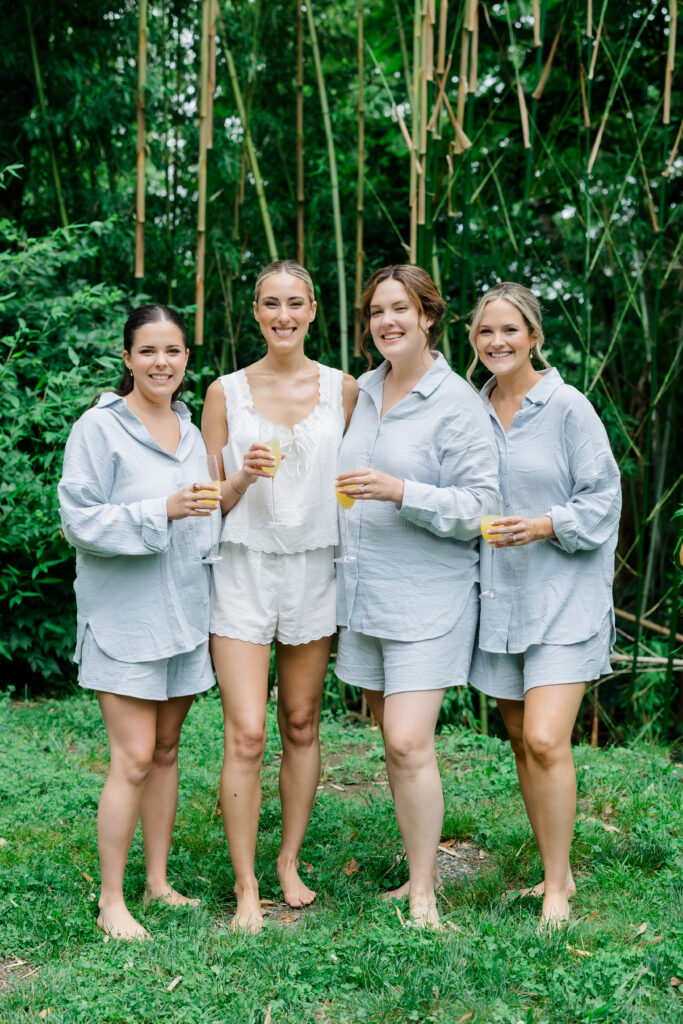 Bride laughing with bridesmaids in matching light blue pajamas during morning preparations in Covington KY.