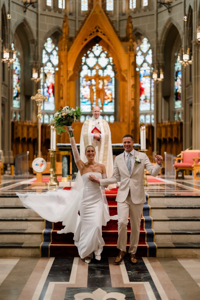 Bride and groom sharing first kiss in front of stained-glass altar at the Cathedral Basilica of the Assumption in Covington KY.