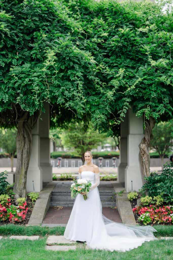 Bride and groom sharing kiss under lush greenery arch in Covington KY garden.