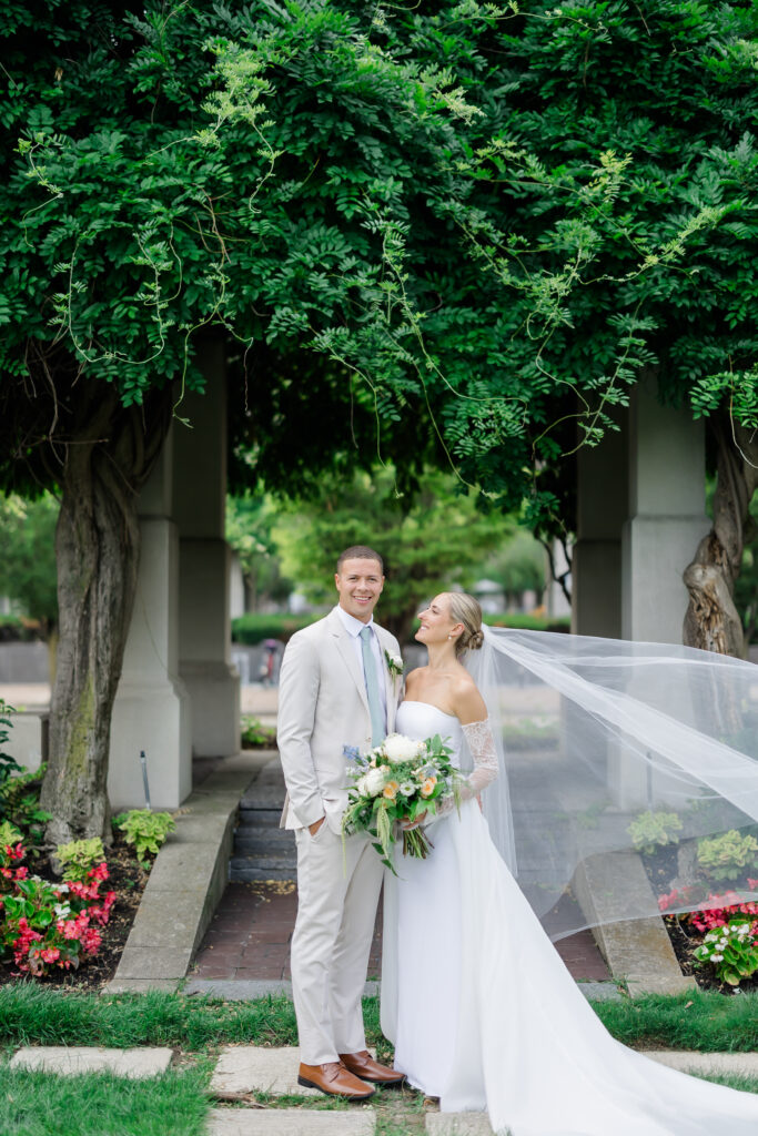 Bride and groom sharing kiss under lush greenery arch in Covington KY garden.