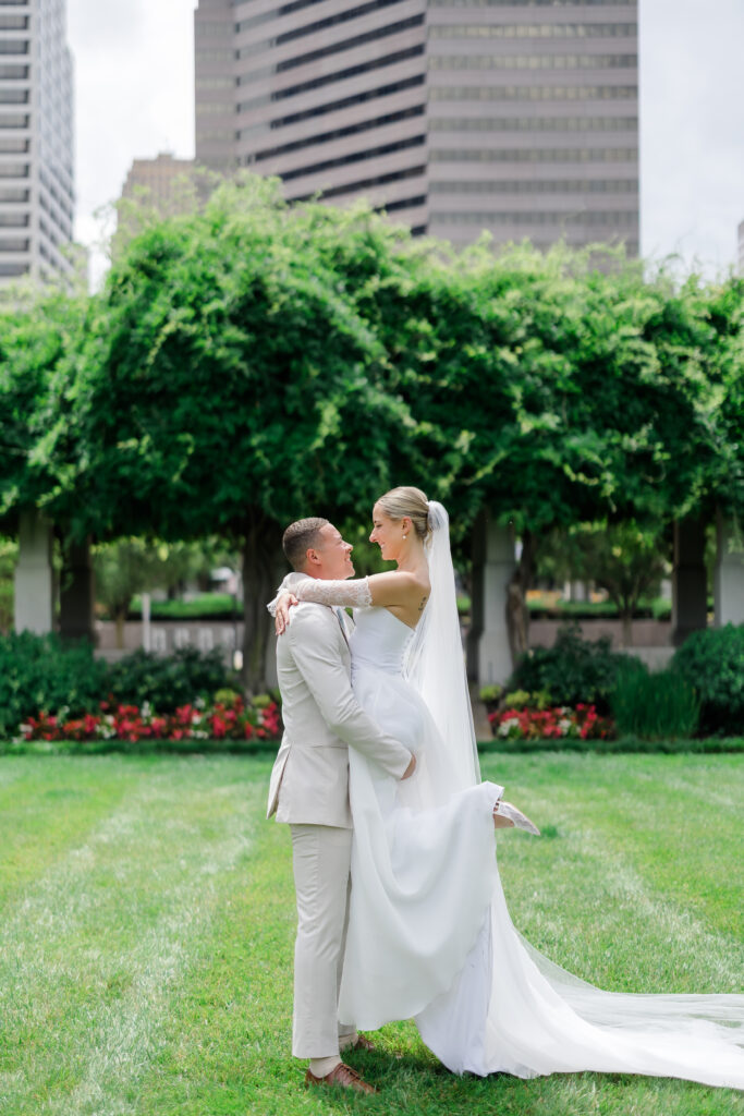 Bride and groom sharing kiss under lush greenery arch in Covington KY garden.