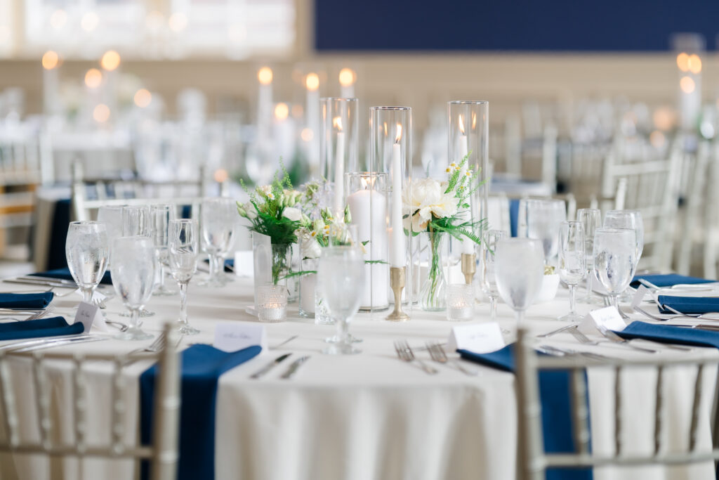 Elegant Grand Ballroom wedding reception with navy table runners, silver chairs, and candlelit centerpieces in Covington KY.